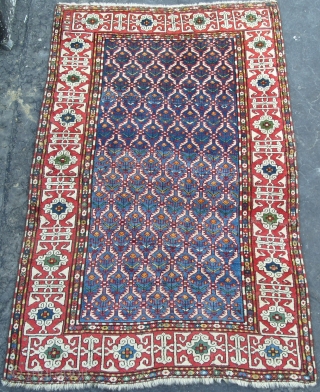 A Splendid Caucasian Kuba Rug with hexagonal lattice design on a light and dark indigo blue field enclosing flowering plants framed by a madder border with white kufi design. All natural dyes,  ...
