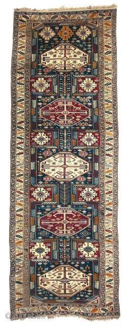 Antique Kuba long rug. Dated 1.904 (AH 1322),  375 x 135cm ( 101,5”x 66”).  
CAUCASIAN
 
This carpet features the appealing “Keyhole Design”. Two of the so-called ‘carnation’ borders, typical of  ...