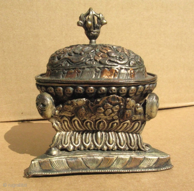 A small vintage Buddhist libations cup, Tibet, made in the form of a Kapala, skull cup, three pieces, the cup, a lid, and a triangular base, silver and copper repousse, decorated with  ...