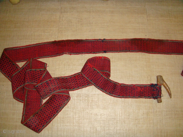 Early 20th Century, Wool, Turkmen Tentband (likely Tekke) with Wooden Wishbone-shaped Fastener. Colour: Deep Red and Black. 
Strap Length (without Rope Fastener): Approx. 997cm ; Strap Width: Approx. 09cm.
Rope Fastener Length (one  ...