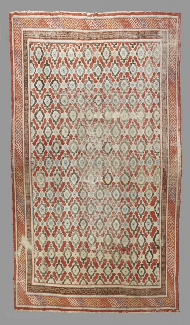 A great early silk rug from East Turkestan. 18th century. In compromised condition with scattered old repairs, wear and some holes but complete. A very rare (possible unique?) tile inspired field design.  ...