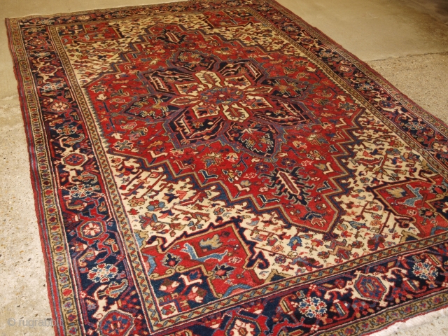 Antique Persian Heriz carpet with a traditional medallion design, medium red field colour with red and blue spandrels. Classic dark indigo blue border that is very well drawn. The central medallion in  ...