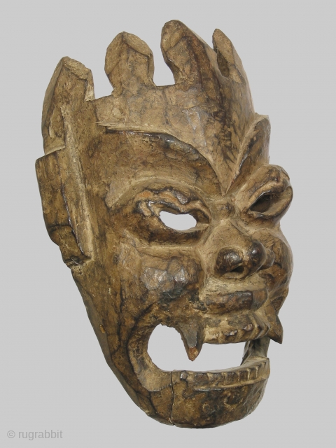 Nepalese or Tibetan mask depicting the diety Mahakala, 12 inches high of dense hardwood, 19th century or possibly earlier. The abstract treatment of the crown, which merges directly into the forehead, is  ...