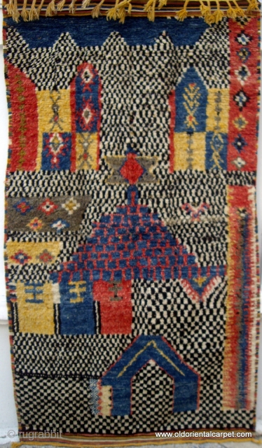 MOROCCAN HIGH ATLAS BERBER RUG. An extraordinary piece, both in design and construction. There are several buildings, probably Mosques and Minarets portrayed in the field. Most unusually, the wool used for the  ...