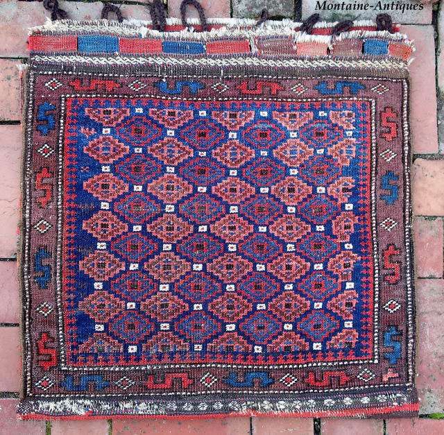 Baluch Pile Bag circa 19th century-- approx 24 × 24” --Repetitive small diamonds on indigo field. The “dollar sign” border is a rare feature used only by a small population of Baluchistan  ...