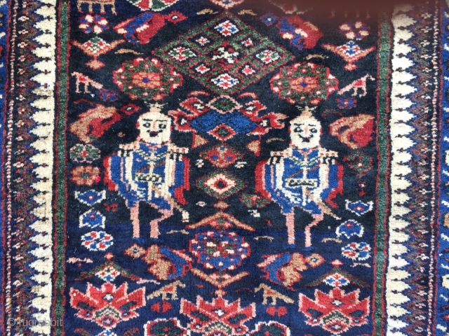 A lovely Persian Bakhtiary long rug displaying two cool looking gentlemen in the centre, size: ca. 345x100cm / 11'3''ft x 3'3''ft , signed and dated at the top. Sides and ends not  ...