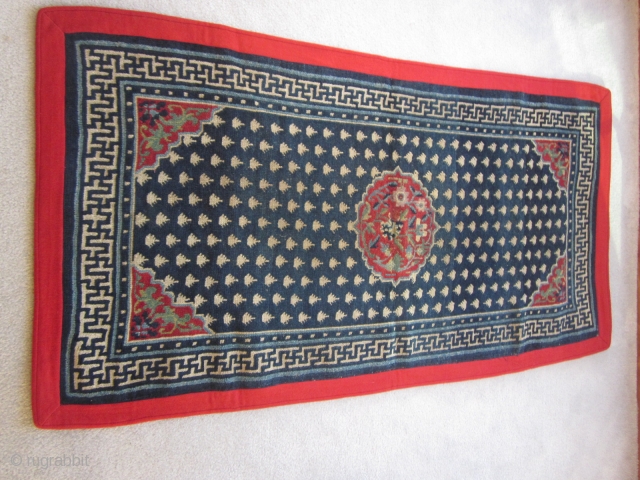 Tibetan khaden, elegant overall frog's foot design on deep indigo ground,cwith a classic running swastika main border and a striking central design with flowers on a good red ground, The four corner  ...