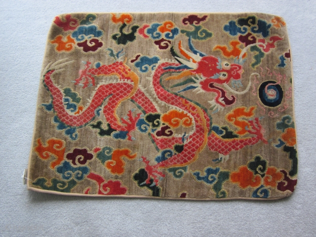 Tibetan mat, 25 by 33 inches, with vivid dragon in an array of synthetic colors. Sewn selvedge edging suggests piece may have been cut from a larger rug. 1930-40    