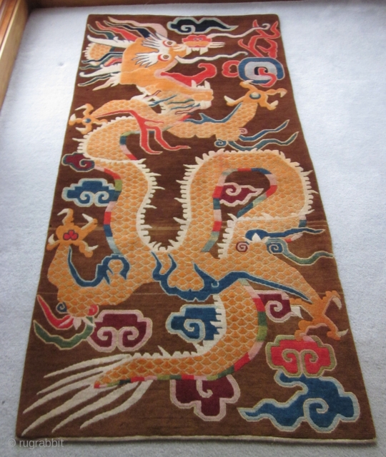 Tibetan, Decorative dragon grasping at flaming pearls in the sky. Playfully drawn on an atypical brown ground. Finely woven c.1930. About 3 by 7 ft. In excellent condition and ready to join  ...