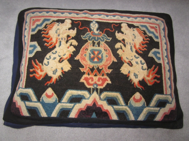 Tibetan mat as large pillow, 18 by 27 inches, note religious symbol of the conch shell, and also the two fish.            