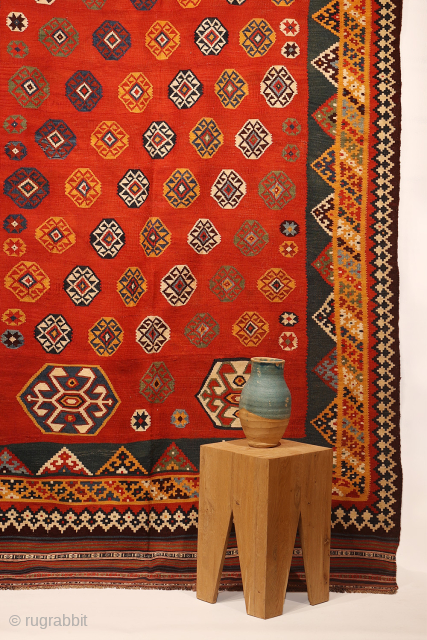 An exquisitely woven antique Qashqai kilim from southwest Iran. The central motifs, the emblem of the Qashqai tribe, is beautifully repeated across the rich terracotta field. The color transitions diagonally, creating a  ...