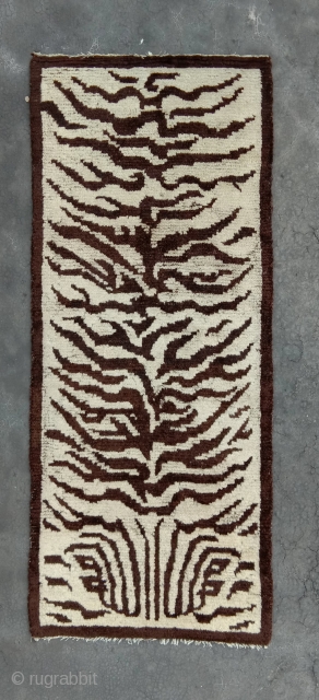 real tiger rug (not fake).. this is a really rare white ground nord west china tiger rug with a fabulous calligraphic drawing.an abstract form of the tiger head is incorporated in the  ...