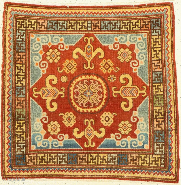 
Khotan Square



Antique Khotan Mat, East Turkestan, with a coffered Gul medallion surrounded by a swastika border  Early 19th century, wool knotted on cotton, approx. 90 x 88 cm, The design of  ...