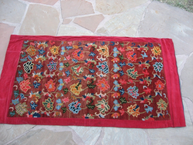 Tibetan Rug  Early 20th century, red cotton corduroy edge and indigo cotton backing.  Small amount of mothing as shown. Otherwise in full pile condition.  5'1" x 2'10" (pile).  