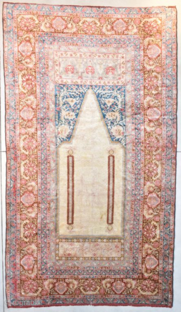 This 3rd quarter 19th century Angora Oushak Oriental Rug measures 6’7” X 11’6”. The prayer design is in ivory containing two columns in rust with a bulbous design at either end of  ...