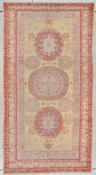 #7790 Khotan Vintage Rug This mid-20th century Khotan Oriental  Rug measures 4’8” x 8’8”. It has three medallions in red, aubergine and very pale green on a pale yellow ground. There  ...