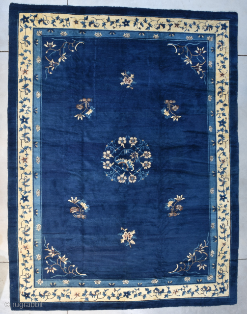This circa 1900 Peking Chinese handmade wool Oriental Rug #8170 measures 9’0” X 11’8”. It has a dark blue field with a floral center medallion surrounded by six flower sprays in ivory,  ...
