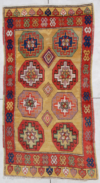 This mid-19th century Konya antique Turkish Carpet measures 3’7” X 6’8”. It has a golden butter colored ground with eight octagon shaped medallions in green, red and  aubergine divided by three  ...