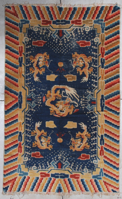 This late 19th century Ningxia measures 4’4’ x 7’0”. It has a navy blue ground with five dragons in yellow gold.   There are cloud motifs in red and gold   ...