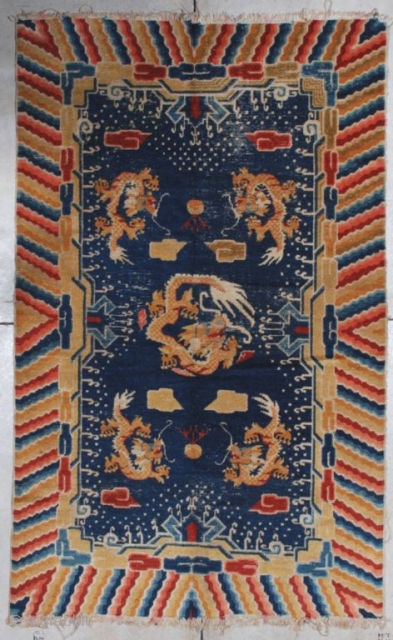 This late 19th century Ningxia (INV 7118) measures 4’4’ x 7’0”. It has a navy blue ground with five dragons in yellow gold.   There are cloud motifs in red and  ...