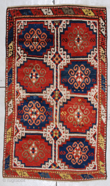 This circa 1875 Caucasian Kazak rug measures 3’9” X 6’6”. It has the Mogan motif in red and blue with ivory negative spaces. It has one narrow border with the lazy S  ...