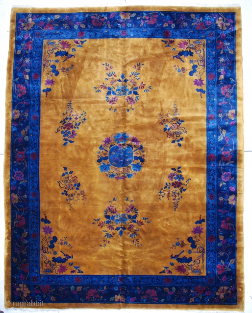 This Mandarin Art Deco Chinese rug measures 9’11” by 12’10”.  It has a yellow gold field with a center medallion containing a bird surrounded by flowers, all in shades of blue,  ...