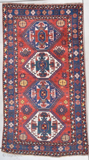 This second half 19th century Kazak measures 4’7” X 8’4” (143 x 256 cm). This is a splendid Kazak. The tomato red ground sports four medallions in green and ivory. The medallions  ...