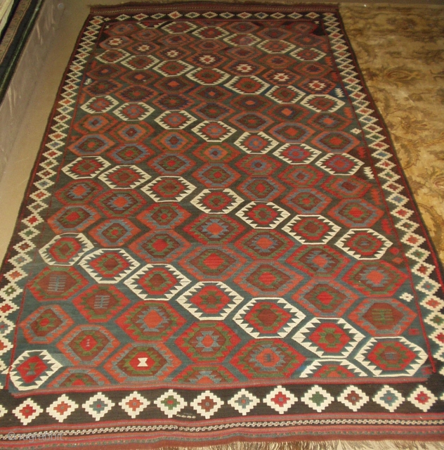 A semi-antique Veramin Kelim, 10'7"x5'3". A repeating pattern of angled gulls in superb earth tone hues dominates the highly abrushed blue ground. Persia, 2nd quarter 20th century.      