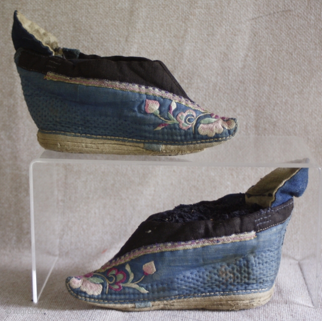 TC 388  This antique Chinese pair of lotus embroidered lotus shoes are most likely from northern china. the vamp is a quilted cotton fabric. Each shoe is embroidered with the same  ...