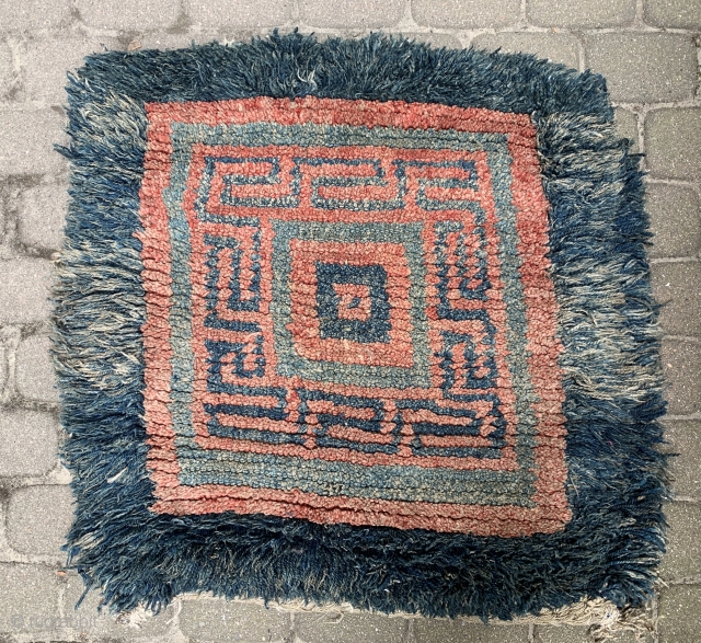 Quite rare and powerful monastic Tibetan seat rug with a square central symbol that shrinks in five steps to the centre. A running dog variant as a border. I would date the  ...