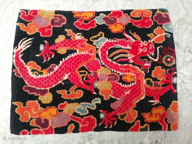 Antique TibetanSingle Rug featuring A Dragon holding Precious jewels surrounded by multi colour clouds in dark blue indigo background.it's not black .
Good age and very good quality..condition too.     