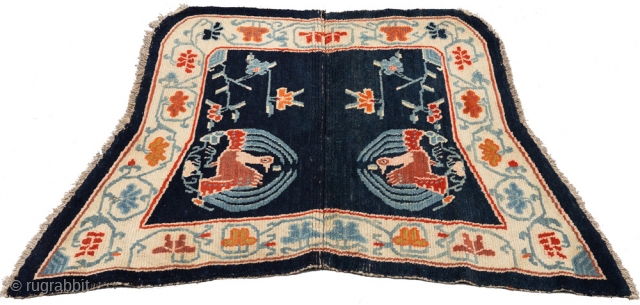 Beautiful 'butterfly' shaped under-saddle carpet from Tibet. The outer main border is of interlinked floral trellis work and has a peacock roundel as the main center field motif, which itself is a  ...