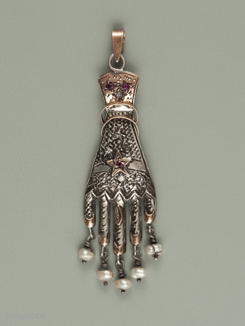 Khomsa, Tunis, Tunisia. Silver, gold, freshwater pearls, ruby and diamond chips
Early to mid-20th century, 2-7/8" (7.3 cm) high, .75" (2 cm) wide. This type of khomsa is difficult to find in Tunisian  ...
