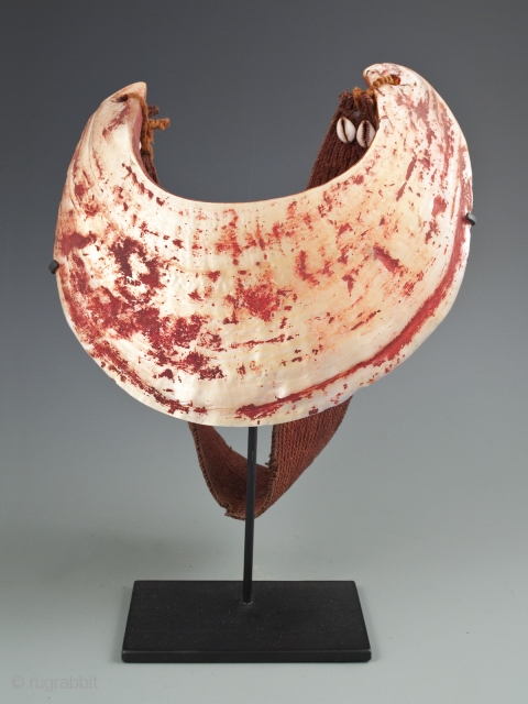 Kina Shell Pectoral,
Western Highlands, Papua New Guinea.
Pearl shell, natural fibers, cowrie shells, natural pigment.
9” high by 8.5” wide, strap is 19.5" long.
Early to mid-20th century.
Ex Robin Lail.      