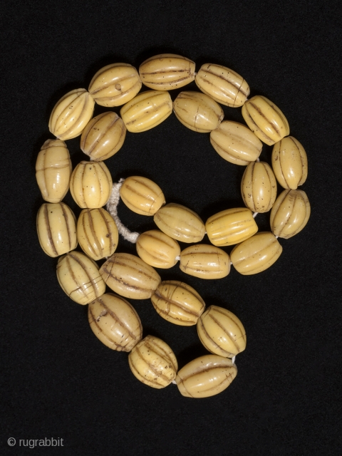 Yellow melon beads,
China or Venice.
Wound glass,
Late 19th century,
26" (66 cm) long as strung, 29 beads.

These beads are found in Irian Jaya and used as bride price. From Robert Liu's book Collectable Beads,  ...