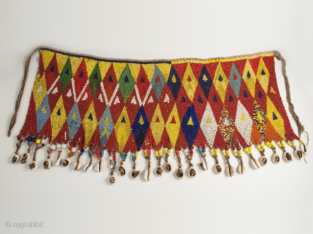 Pikuran (cache-sexe), Bana Guili people, Mandara Mountains, Cameroon. Seed beads, cotton string, cowrie shells, 19" (48.3 cm) wide by 9.5" (24 cm) high, mid 20th century or earlier.

The incredible variety of colored  ...