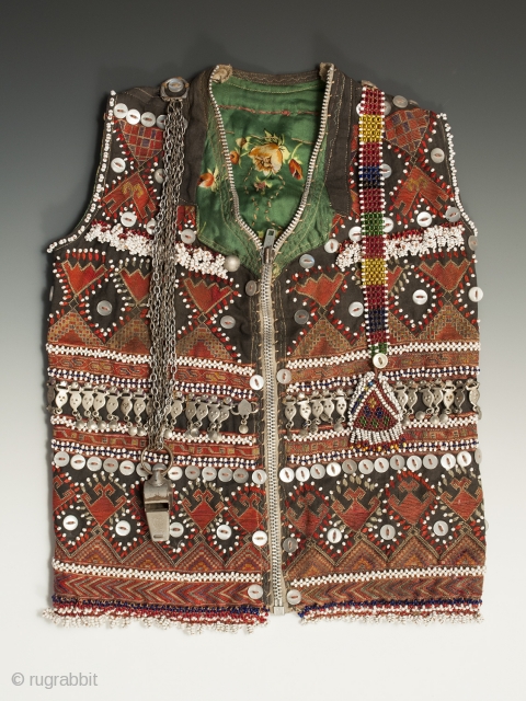 A very special child's vest from the Kohistan area of Pakistan. It is finely embroidered and extravagantly decorated with beads, buttons, and silver ornaments. There is a charming whistle on the front,  ...