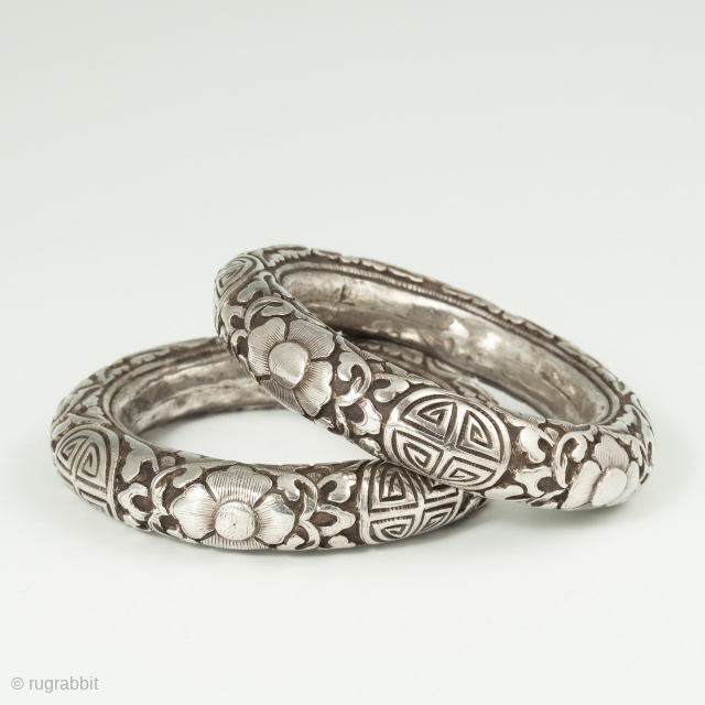 A matched pair of silver repoussé bracelets from China, with the Shòu symbol for long life amidst floral scroll work. Interior circumference of 7.75 inches (19.5 cm), 5/8 inch wide (1.5 cm).  ...