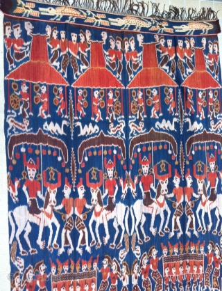 Outstanding example of Sumba Hinggi Ikat. A festive ceremonial parade. Large group of people riding on horses and parading while other people carrying an ark field with ladies, on their shoulders. Other  ...