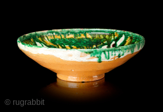 A Samanid splashware bowl
Samarkand, 10th century
Of conical form on short foot with straight lip, the sgraffiato decoration with a large, stylised flower with two leaves, with yellow and green splashes and clusters  ...