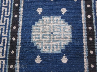 Tibetan: Vintage khaden, 2'3" by 4'6", with latch hook central medallion in light blue and frog's feet on a saturated indigo ground, before 1900. Some scattered re-piling.      