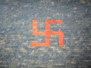 Tibetan khaden, pre-1900, 2'5" by 4'6", three eccentric swastikas on an abrashed blue ground, some quality repiling in field              