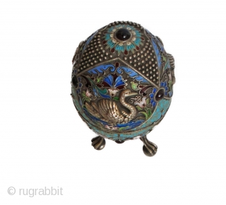 RUSSIAN SILVER FIGURAL JEWELED FOOTED EGG BOX

A Russian silver enameled egg box depicting swans and flowers with filigree and beaded design throughout. Holds cabochon ruby to top with three rubies set to  ...