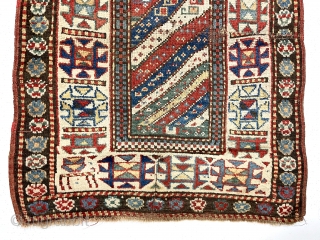 Antique Caucasian Kazak rug with interesting design features and a very unusual narrow size. The weaver altered an otherwise typical diagonal striped field with width and design changes. The extra wide ivory  ...