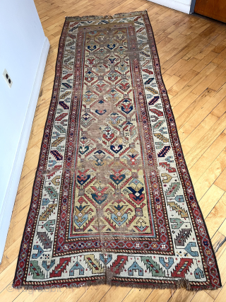 Early Caucasian long rug with a rich yellow ground and floral palmette lattice. Probably described as “gendge” for lack of a better name. Intact but with some heavy wear and exposed foundation.  ...