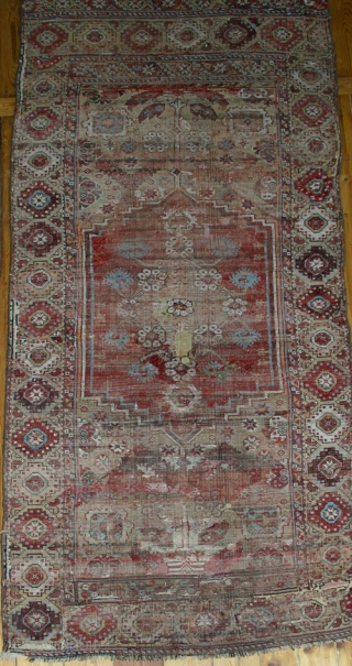 18th century Konya rug,W/W,225x110 cm.
Numerous repilings, inserts, loss of the small lateral outer borders. A unique central axis design that devides the entire field and incorporates the medaillon.     