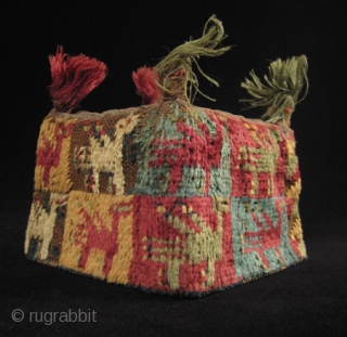 A colorful four-cornered hat from the Huari culture of the Highlands of Peru. Made of camelid wool yarns and natural dyes, it has a mesh screen on the top to contain the  ...