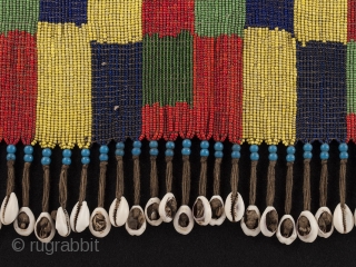 Pikuran (cache-sexe, Bana Guili people, Mandara Mountains, Cameroon. Seed beads, cotton string, cowrie shells. 16.25" (41.2 cm) wide by 8.25" (21 cm) high. With base 20.75" (52.7 cm) wide by 12.25" (31  ...