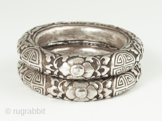 A matched pair of silver repoussé bracelets from China, with the Shòu symbol for long life amidst floral scroll work. Interior circumference of 7.75 inches (19.5 cm), 5/8 inch wide (1.5 cm).  ...